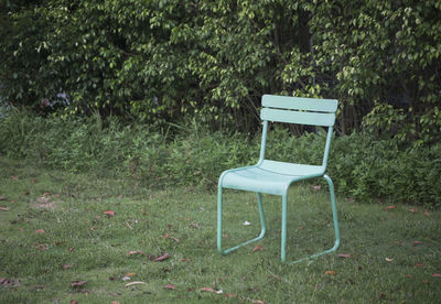 Empty bench on field by trees in park