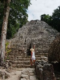 Rear view of woman standing on rock against trees