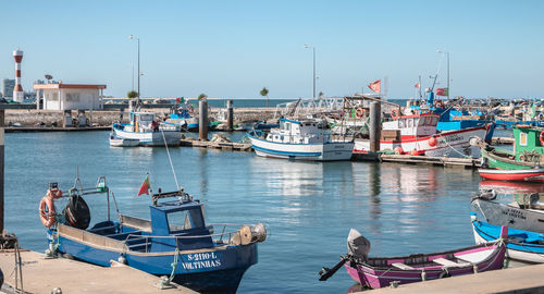 Boats moored at harbor against clear sky