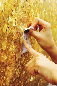 Cropped image of hands holding paper on weathered wall