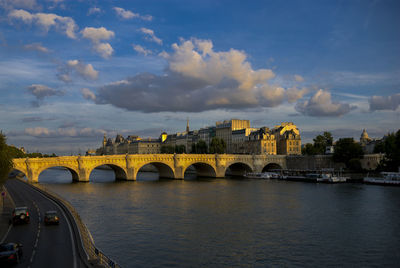 Arch bridge over river against cloudy sky