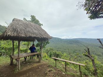 Man sitting on roof against sky