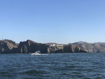 Scenic view of sea and mountains against clear blue sky