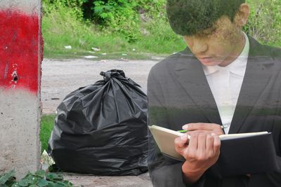 Double exposure image of businessman writing in diary and garbage bag