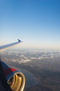 Airplane flying over landscape against clear sky