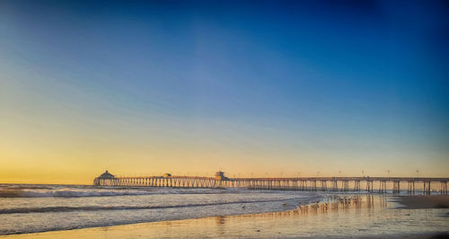 Pier over sea against sky during sunset