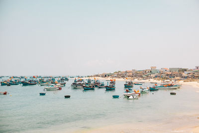 Boats moored at harbor against clear sky