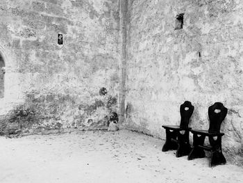 Wooden chairs by old building wall