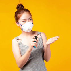 Portrait of young woman with yellow hair against orange background