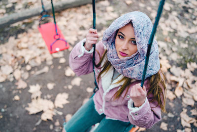 Portrait of girl sitting on swing in park during autumn