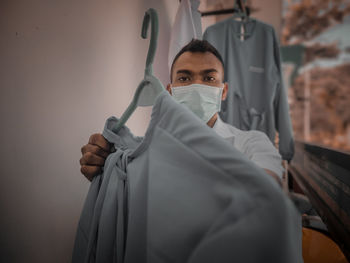 Portrait of man wearing face mask holding uniform