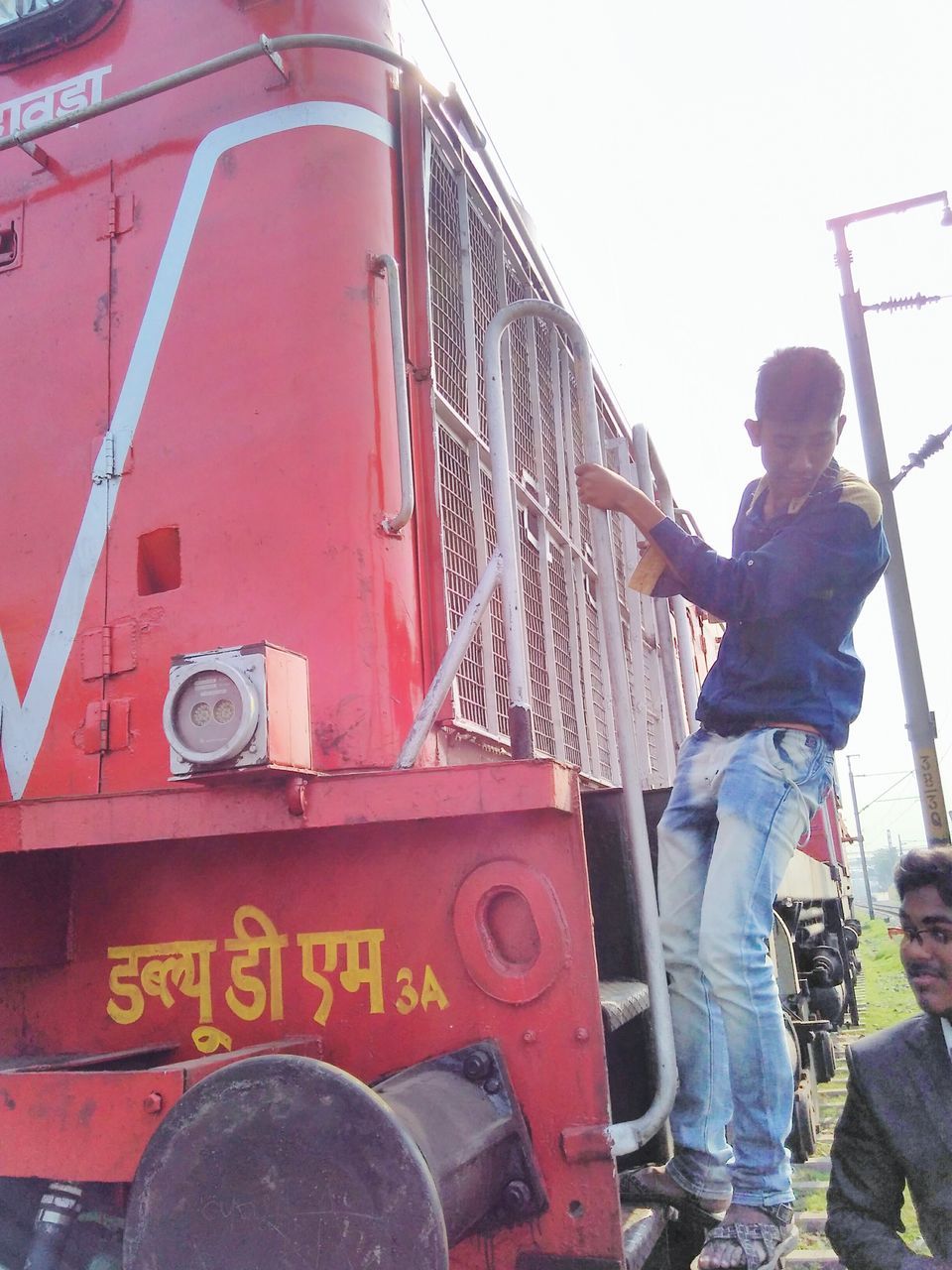 transportation, mode of transport, land vehicle, red, train - vehicle, communication, men, metal, travel, rail transportation, technology, text, day, public transportation, low angle view, connection, outdoors, passenger train