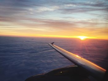 Airplane flying over sea against sky during sunset