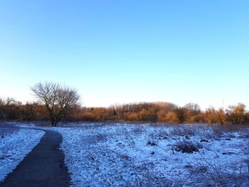 View of snow covered field against clear sky