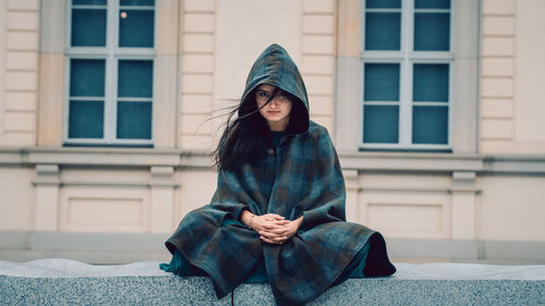 Portrait of woman sitting against building