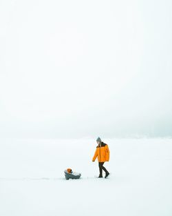 Man with umbrella walking on snow covered landscape