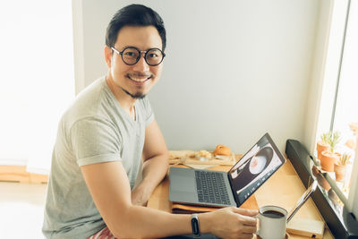 Portrait of happy smiling man work with laptop on his workspace desk.