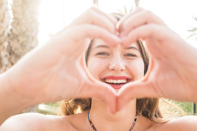 Portrait of young woman making heart shape