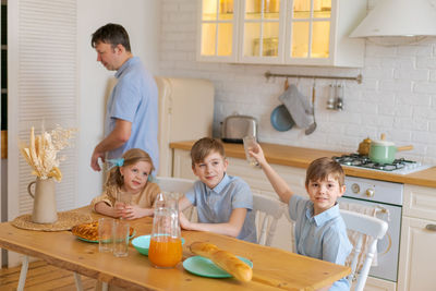 Large family with teenage children eating breakfast in kitchen. caucasian