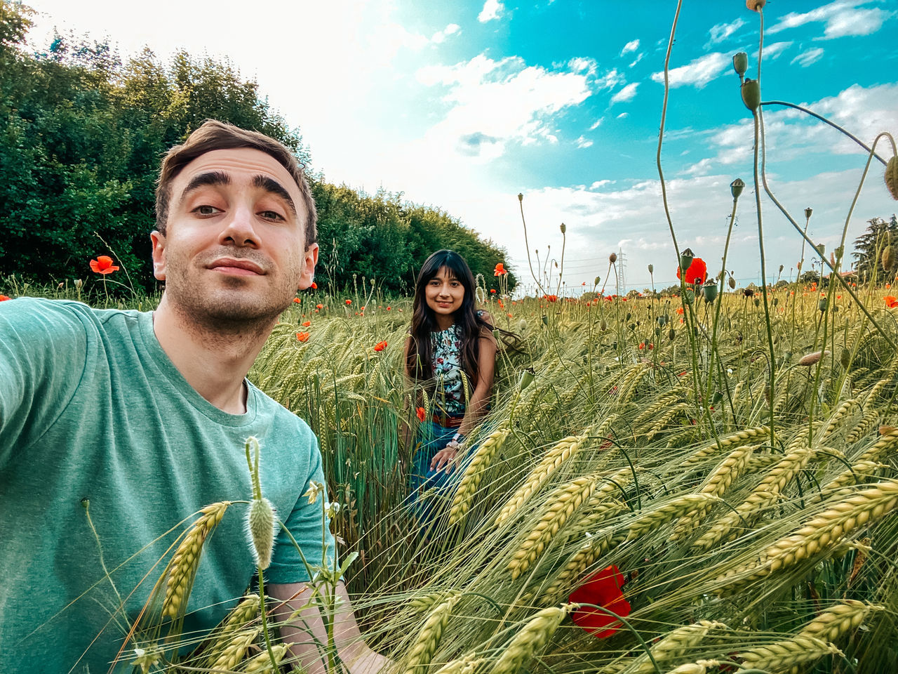 plant, sky, adult, nature, young adult, men, crop, two people, smiling, agriculture, field, land, landscape, portrait, growth, happiness, rural scene, casual clothing, emotion, leisure activity, day, tree, togetherness, lifestyles, cloud, women, flower, outdoors, environment, looking at camera, front view, grass, cereal plant, beauty in nature, green, summer, food, food and drink, sunlight, looking, farm, rural area, waist up, holiday, enjoyment