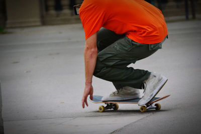 Low section of man skateboarding on road