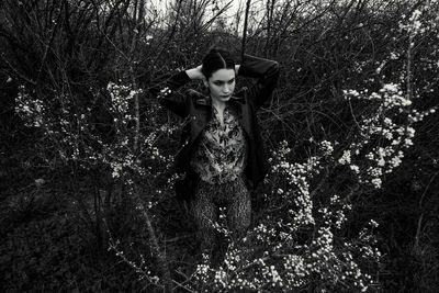 Portrait of young woman standing by tree in forest