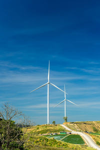 Windmills on landscape against blue sky