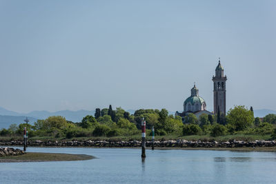 Scenic view of river by building against clear sky