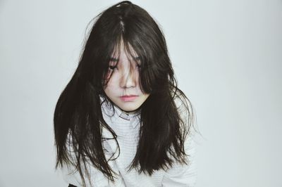 Close-up of young woman with eyes closed against white background