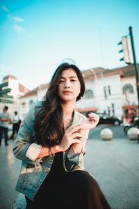 Young woman holding ice cream on street in city