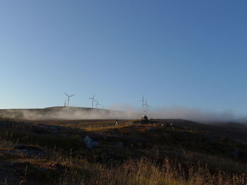 Wind turbines on field against clear sky