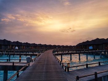 Pier over sea against sky during sunset