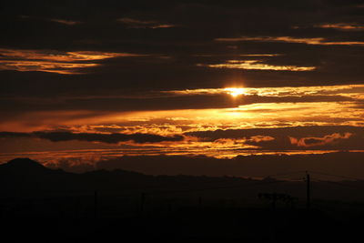 Scenic view of dramatic sky over silhouette landscape