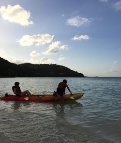 Men in boat on lake against sky