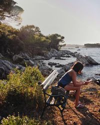 Side view of woman standing by tree against sky