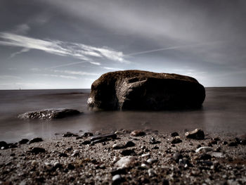 Rock formation on beach against sky