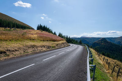 Road amidst field against sky