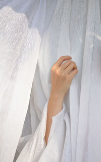 An asian woman hand in background of a white voile curtain