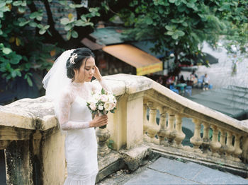 Bride holding flowers while standing outdoors