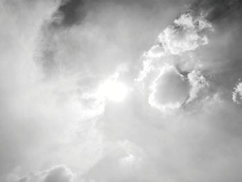 Low angle view of sunlight streaming through clouds