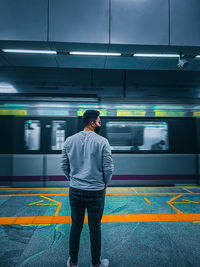 Rear view of man standing on subway station