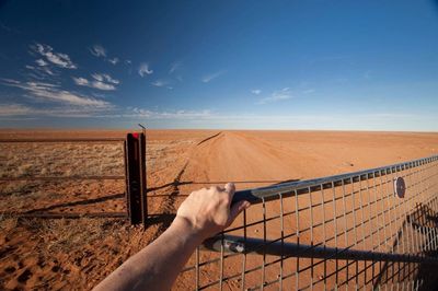 Cropped hand of fence against landscape