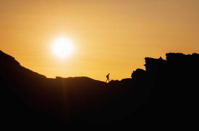 Silhouette person on land against sky during sunset