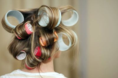 Rear view of woman with hair curlers at salon