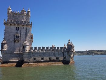 View of historic building by sea against clear sky