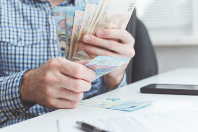 Midsection of man holding paper