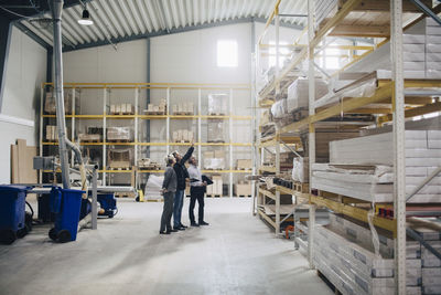 Full length of business people looking at rack in lumber industry