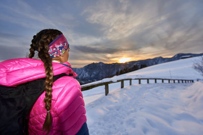 Rear view of woman with umbrella against sky during winter