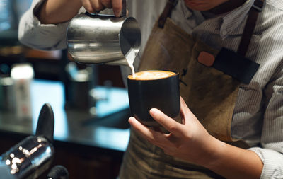 Midsection of owner making coffee at shop