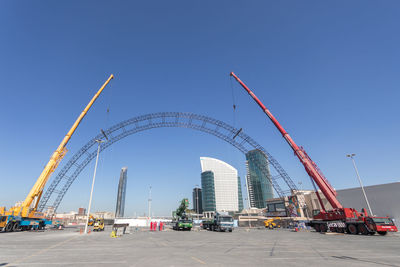 Ferris wheel by buildings against clear blue sky